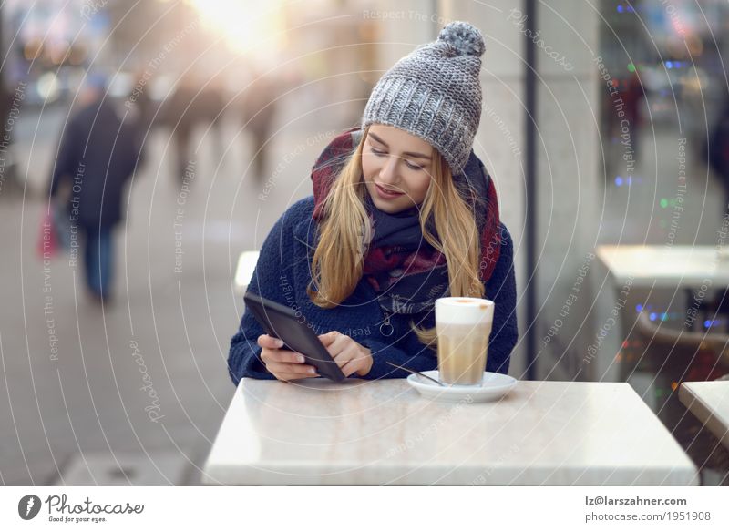 Junge blonde Frau mit mobilem trinkendem Kaffee Latte Macchiato Lifestyle Glück schön Gesicht lesen Winter Tisch Technik & Technologie Erwachsene Zeitung