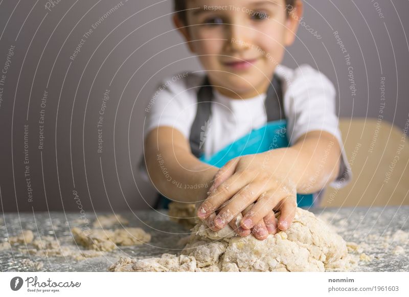 Kleiner Junge, der rohen Pizzateig knetet Teigwaren Backwaren Brot Freude Spielen Küche Kind Lächeln machen blau reizvoll Schürze backen Bäcker Kaukasier heiter