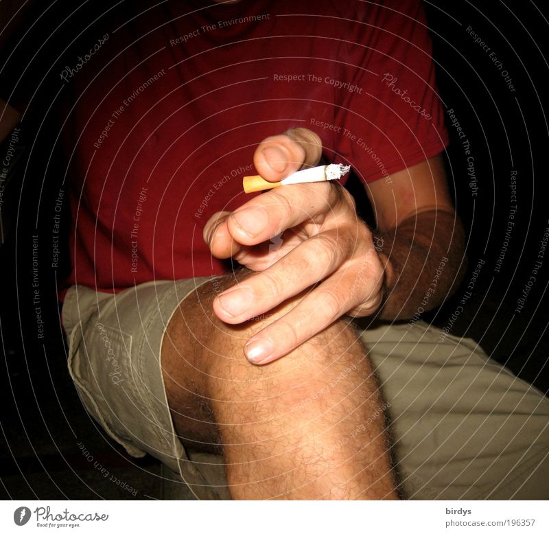 sitzender Mann mit kurzen Hosen und brennender Zigarette in der Hand maskulin Erwachsene Finger Beine 1 Mensch T-Shirt Rauchen rot Laster Nervosität Genusssucht