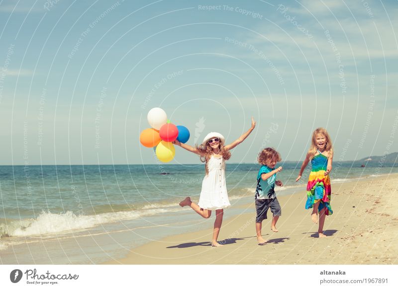 Drei glückliche Kinder mit den Ballonen, die auf den Strand tanzen Lifestyle Freude Glück schön Erholung Freizeit & Hobby Spielen Ferien & Urlaub & Reisen