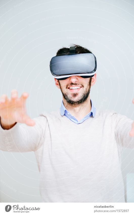 Mann mit VR-Brille sucht und lächelt virtuelle Realität Freude Spielen Computerspiel Expedition Erfolg Büro Medienbranche Business Sitzung Headset