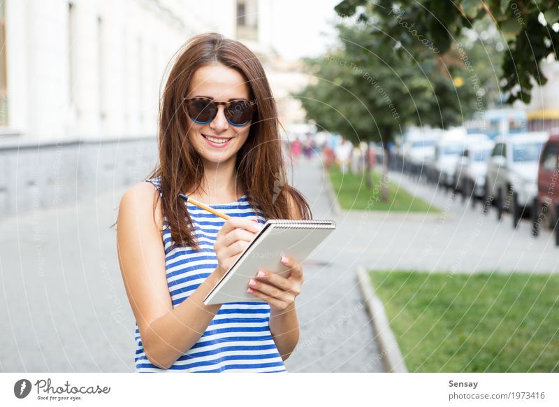 Mädchen mit einem Notizbuch auf der Straße Glück schön Ausflug Sommer Mensch Frau Erwachsene Jugendliche Musiknoten Buch Park Mode Sonnenbrille Papier