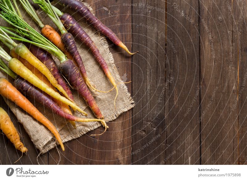 Frische organische Regenbogenkarotten auf einem Holztisch Gemüse Ernährung Vegetarische Ernährung frisch braun gelb Möhre Landwirt Lebensmittel Ernte Gesundheit