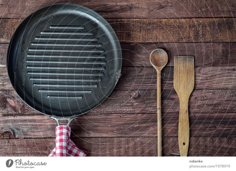 Leere Grillpfanne und hölzerne Kochgeräte Pfanne Löffel Tisch Küche Restaurant Stoff Holz Metall oben braun schwarz Geschirr Tischwäsche Spachtel Aussicht