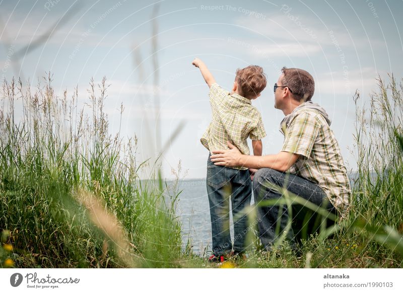 Vater und Sohn, die am Park nahe See zur Tageszeit spielen. Lifestyle Freude Leben Erholung Freizeit & Hobby Spielen Ferien & Urlaub & Reisen Ausflug Freiheit