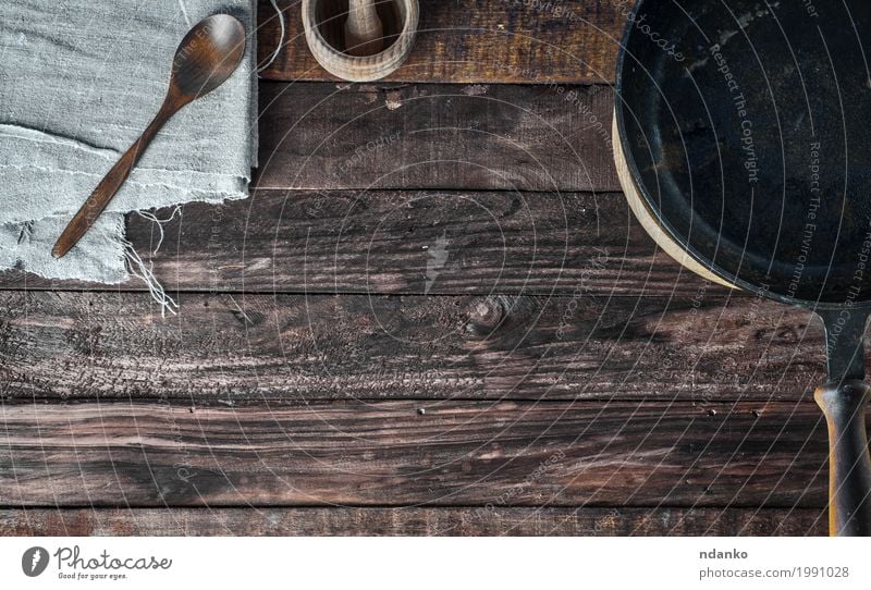 Hölzerner Hintergrund Browns mit schwarzer Bratpfanne Geschirr Pfanne Löffel Tisch Küche Restaurant Stoff Holz Metall oben Sauberkeit braun Tischwäsche Kopie