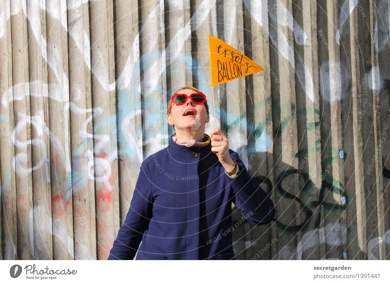 Frau im Mantel mit Brille und Wimpel vor Graffitiwand aus Beton Lifestyle Feste & Feiern Geburtstag feminin Junge Frau Jugendliche 1 Mensch Sonnenbrille