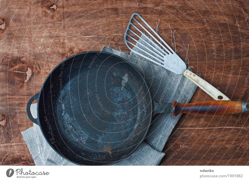 Roheisenschwarzbratpfanne mit Kücheneisenschaufel Geschirr Pfanne Tisch Restaurant Werkzeug Stoff Holz Metall oben Sauberkeit braun Tischwäsche Spachtel Kopie