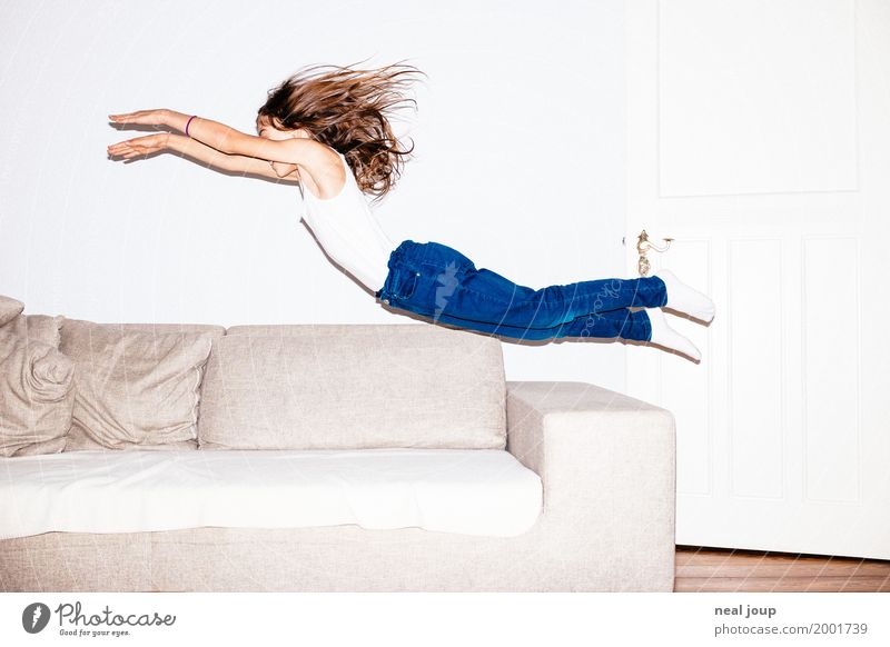 Langhaariges Mädchen in Jeans springt kopfüber in ein Sofa feminin Kind 8-13 Jahre Kindheit Jeanshose brünett langhaarig fliegen springen frech Fröhlichkeit