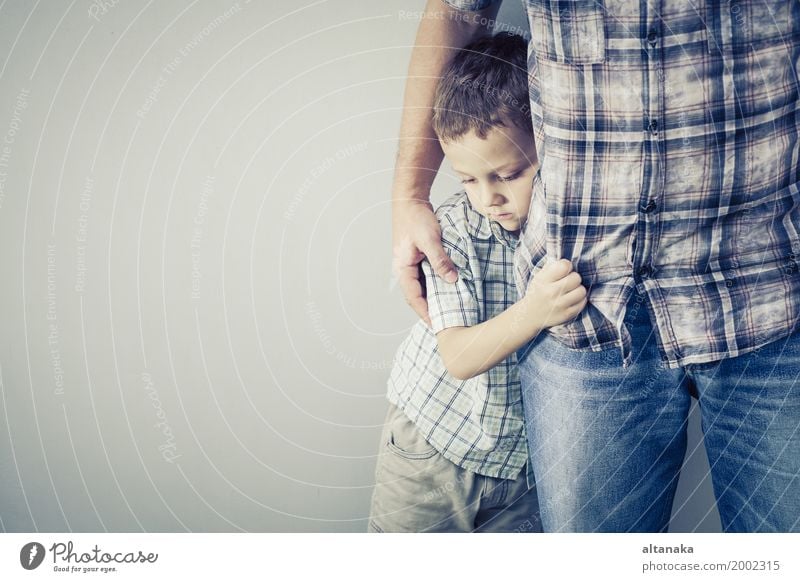 trauriger Sohn, der seinen Vater tagsüber nahe der Mauer umarmt Gesicht Kind Junge Mann Erwachsene Eltern Familie & Verwandtschaft Kindheit Traurigkeit Umarmen