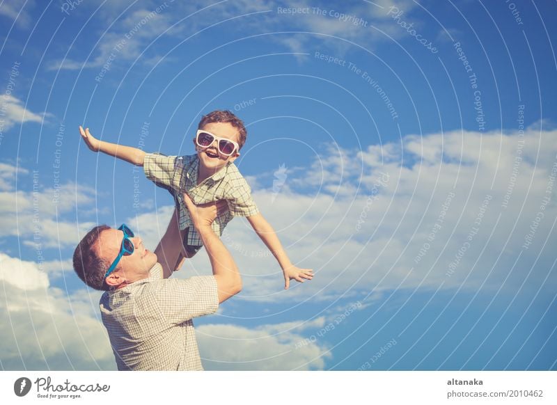 Vater und Sohn spielen im Park zur Tageszeit. Konzept der freundlichen Familie. Bild auf dem Hintergrund des blauen Himmels gemacht. Lifestyle Freude Leben