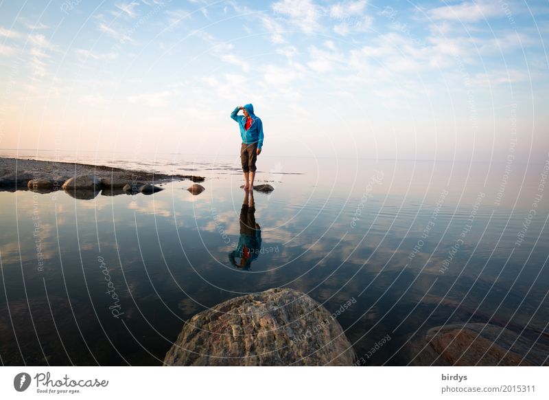 Mann mit türkisfarbenem Hoody steht auf einem Stein im Meer und blickt in die Ferne Zufriedenheit ruhig maskulin Erwachsene 1 Mensch 45-60 Jahre Wasser Himmel