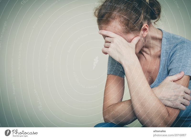 eine traurige Frau, die an einer Wand sitzt und ihren Kopf in den Händen hält Lifestyle Gesicht Mensch Mädchen Erwachsene Familie & Verwandtschaft Traurigkeit