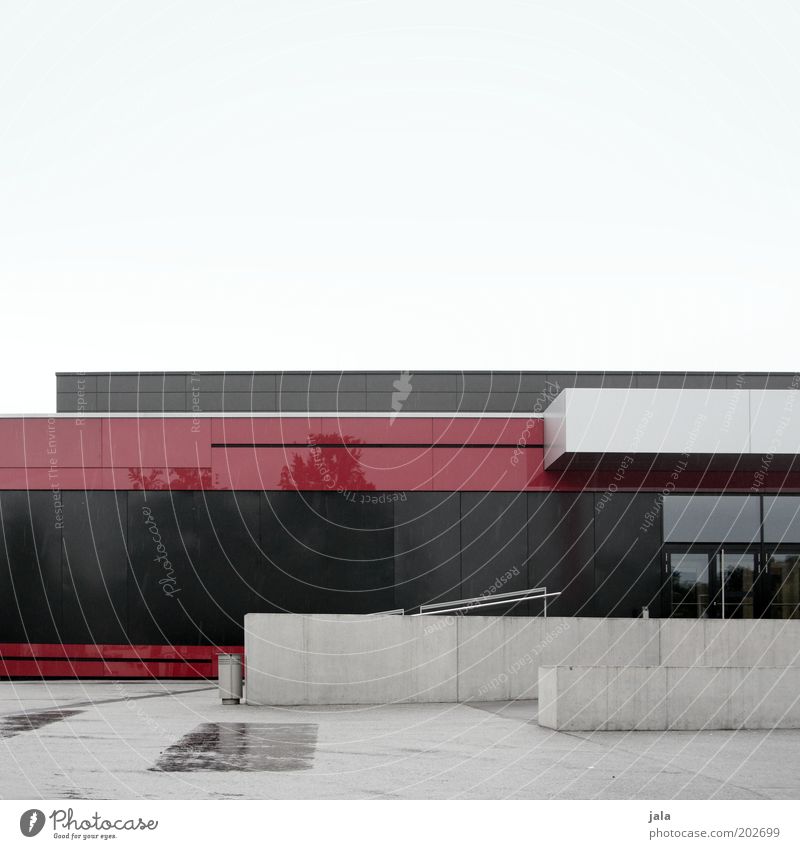 mehrzweckhalle Menschenleer Haus Platz Bauwerk Gebäude Architektur Halle Mauer Wand Treppe Fassade Tür groß trist grau rot schwarz Farbfoto Außenaufnahme