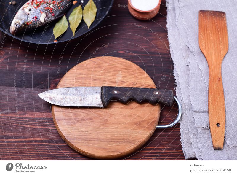 Küchenmesser auf einem Kreisausschnitt-Holzbrett Fisch Essen Pfanne Messer Tisch alt retro braun grau schwarz Holzplatte Top Karpfen Spachtel Serviette Koch