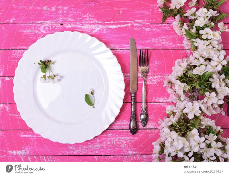 Weißer Teller auf einer rosa Holzoberfläche Mittagessen Abendessen Besteck Messer Gabel Tisch Küche Restaurant Blume Papier Metall Stahl alt oben retro weiß