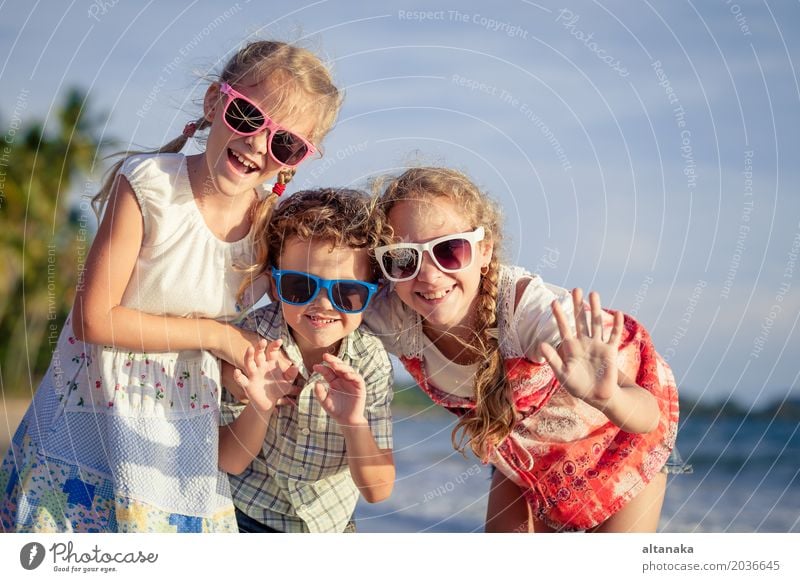 Drei glückliche Kinder stehen am Strand am Tag. Menschen haben Spaß im Freien. Konzept der freundlichen Familie und der Sommerferien. Lifestyle Freude Glück