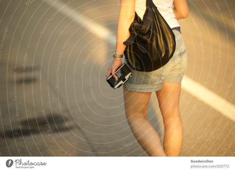 Suchend Mensch feminin Junge Frau Jugendliche 1 Straßenverkehr Fotokamera gehen tragen warten nah schön Gefühle Stimmung Frühlingsgefühle Farbfoto Außenaufnahme