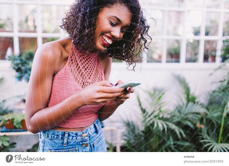 Afroamerikanische glückliche Frau, die eine Nachricht auf dem Smartphone schreibt. Lifestyle Freude Glück Sommer Garten Entertainment Telefon Handy PDA
