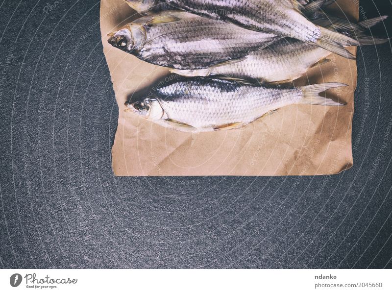 ganzer getrockneter Fisch in den Plötzenschuppen Ernährung Papier alt oben retro grau schwarz gesalzen trocknen Karpfen Schafsbock Lebensmittel Hintergrund