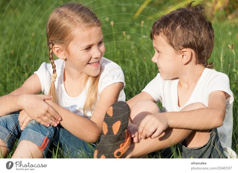 Zwei glückliche Kinder, die nahe einem Baum auf dem Gras spielen Lifestyle Freude Glück schön Gesicht Freizeit & Hobby Spielen Ferien & Urlaub & Reisen Freiheit