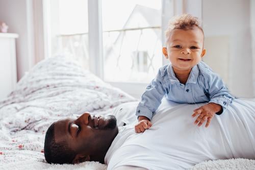 Junger afroamerikanischer Vater und Kleinkind kuscheln zusammen. Lifestyle Freude Glück Schlafzimmer Mensch maskulin Baby Junger Mann Jugendliche Erwachsene