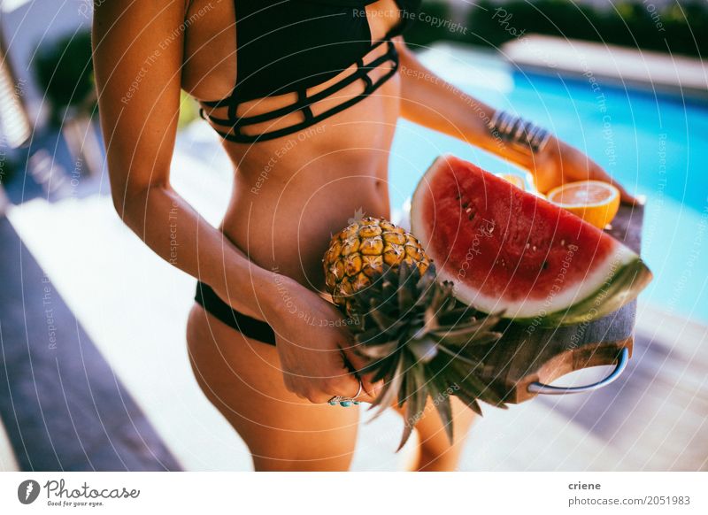 Junge Frau, die frische Früchte auf hölzernem Brett dient Frucht Ernährung Essen Lifestyle Glück Schwimmbad Ferien & Urlaub & Reisen Sommer Erwachsene Bikini