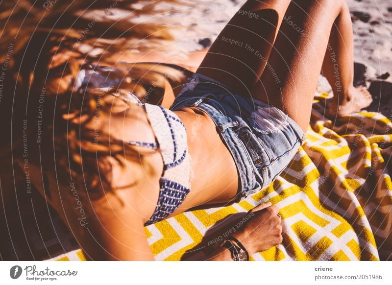 Frau, die am Strand am sonnigen heißen Sommertag sich bräunt und sich entspannt Lifestyle Freude Körper Wellness Erholung Freizeit & Hobby