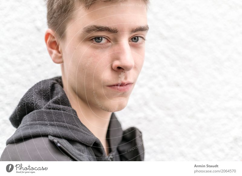 Porträt eines lächelnden jungen Mannes männlich Junge Teenager selbstbewusst Kaukasier Lächeln Grinsen Stehen Wand weiß glücklich Jacke schwarz Lifestyle Jugend