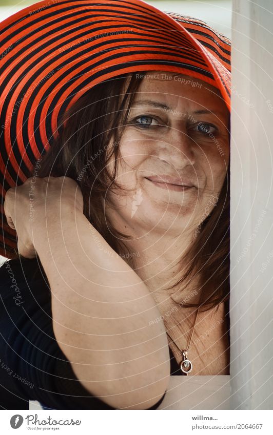 Lächelnde reife Frau mit rotem Hut feminin Erwachsene Mensch Halskette brünett direkt Porträt Blick in die Kamera attraktiv gestreift Streifen freindlich Flirt