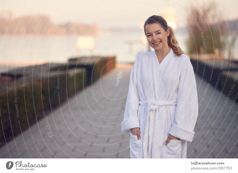 Lächelnde junge Frau in einem weißen Bademantel Glück Erholung Spa Garten Feierabend Erwachsene 1 Mensch 18-30 Jahre Jugendliche See stehen Fröhlichkeit