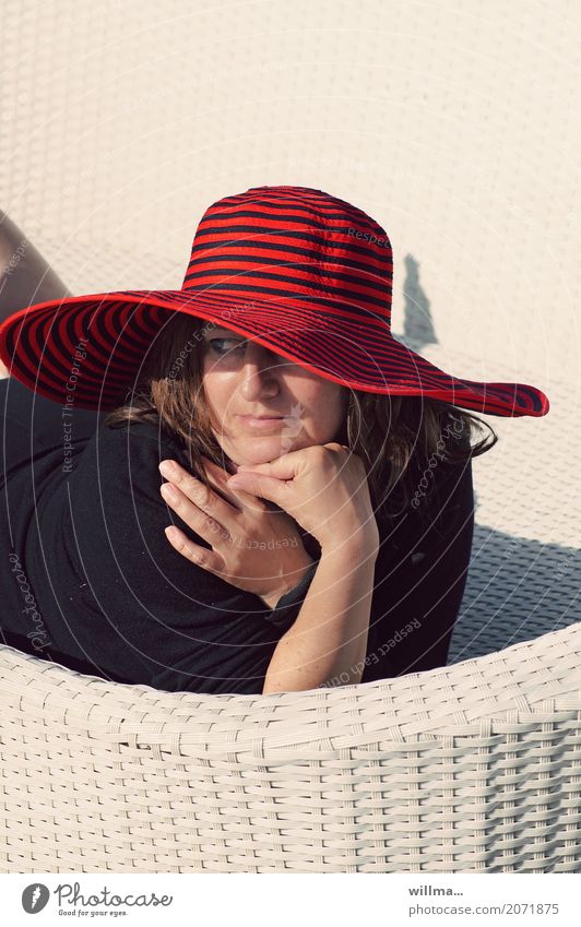Frau mit rotem Hut liegt auf weißer Korbliege und genießt die Sonne Mensch feminin Erwachsene Leben Sommer Erholung Sonnenbad Dame Porträt Wegsehen Lady