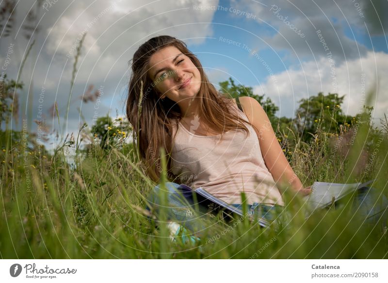 Junge Frau auf der Wiese lächelt und kneift ein Auge zu Bildung lernen feminin Jugendliche 1 Mensch 18-30 Jahre Erwachsene Natur Himmel Wolken Sommer