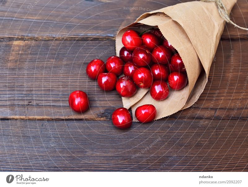 Rote reife Kirsche in einer Papiertüte Frucht Dessert Essen Vegetarische Ernährung Saft Sommer Tisch Natur Holz frisch natürlich oben retro saftig rot
