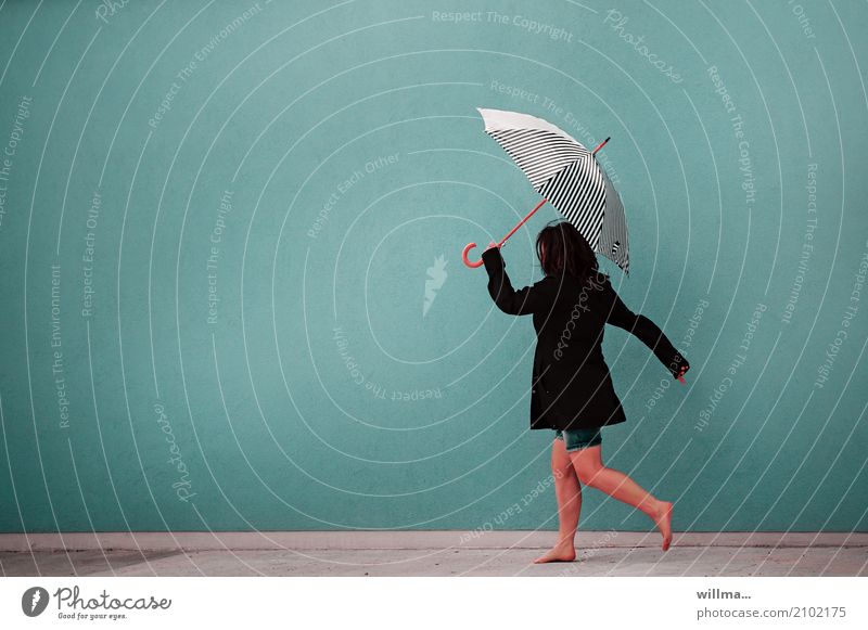 Frau läuft beschwingt mit Regenschirm und barfuß vor neutraler Wand, in kurzen Hosen und Jacke Mensch feminin Erwachsene 1 schwarzhaarig laufen rennen