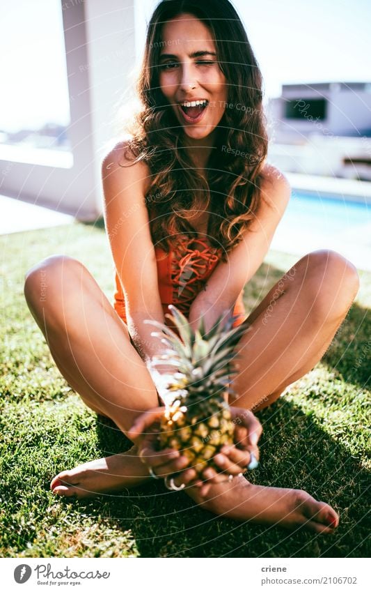 Junge attraktive Frau, die im Garten sitzt und eine Ananas hält Frucht Lifestyle Freude Glück Ferien & Urlaub & Reisen Sommer Sommerurlaub Mensch feminin
