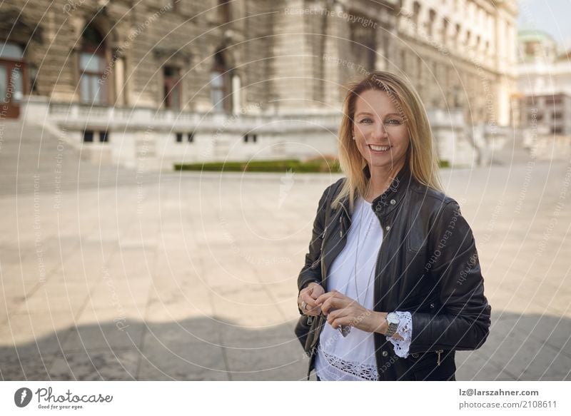 Attraktive Frau, die in einem städtischen Quadrat steht Glück Gesicht Erwachsene 1 Mensch 30-45 Jahre Palast Gebäude blond Lächeln stehen historisch attraktiv