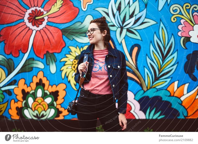 Junge attraktive Frau mit Brille, Jeansjacke und Spiegelreflexkamera vor bunter Wand feminin Junge Frau Jugendliche Erwachsene 1 Mensch 18-30 Jahre 30-45 Jahre