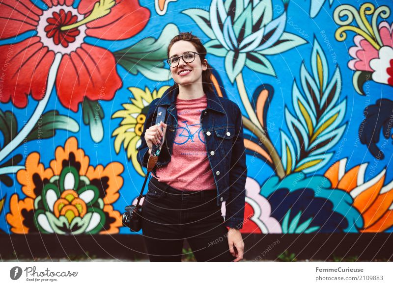 Young woman in front of colorful graffiti wall feminin Junge Frau Jugendliche Erwachsene 1 Mensch Lebensfreude Wandmalereien Straßenkunst Blüte Blume mehrfarbig