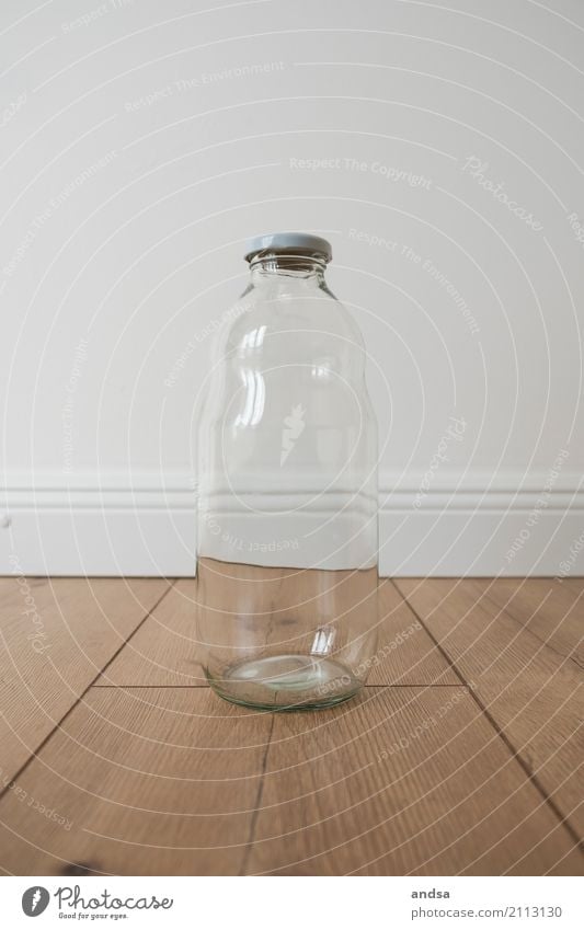Leere Milchflasche auf einem Holzboden vor einer weißen Wand Glasflasche leer Flasche weiße Wand weißer Hintergrund Fußleiste Kunst Stillleben Innenaufnahme
