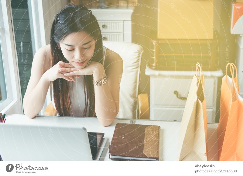 Glückliche junge asiatische Frau, die das on-line-Einkaufen tut Erholung Haus Sofa Geldinstitut Computer Notebook Technik & Technologie Internet Erwachsene Buch