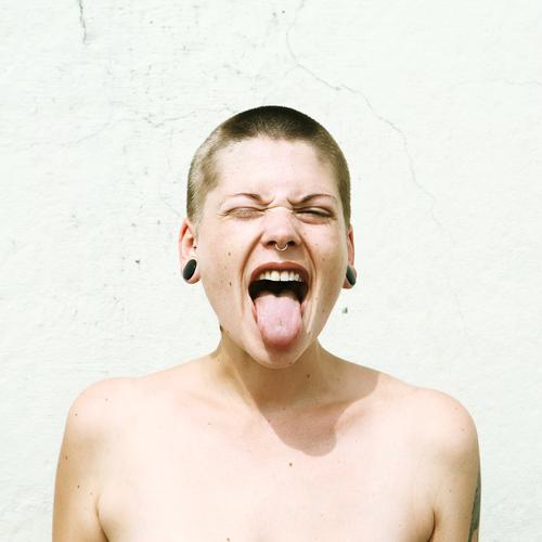 Junge Frau mit kurzen Haaren streckt die Zunge raus Lifestyle Stil schön Jugendliche Gesicht 18-30 Jahre Erwachsene Jugendkultur Subkultur Mauer Wand Schmuck