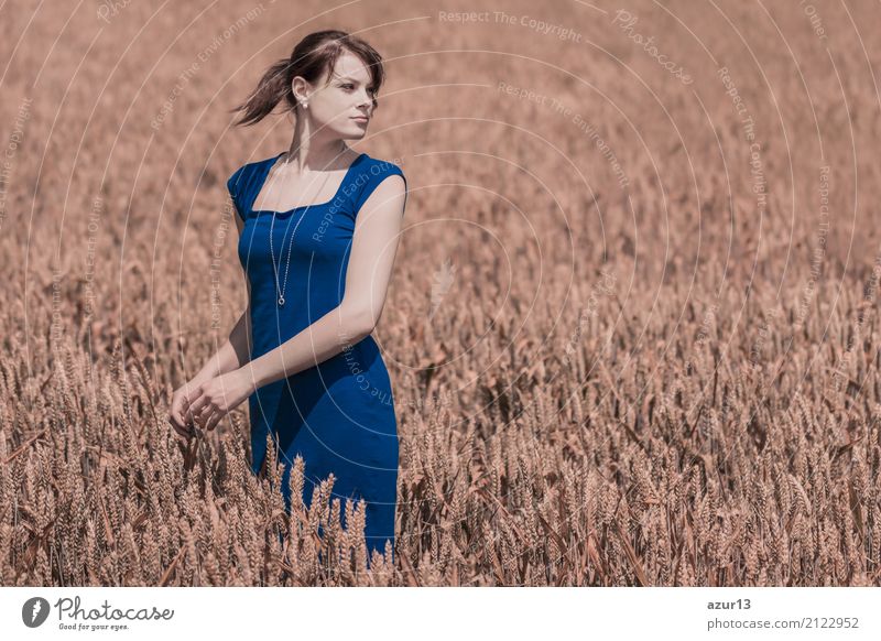 Schöne junge Frau mit blauem Kleid im Herbst auf Getreide Feld bis zum Horizont. Hübsches Mädchen mit Lebensfreude geniesst die Sonnenschein Pause und das Leben. Erholung und Energie tanken vom Zeit Stress in der Umwelt und Natur Idylle.
