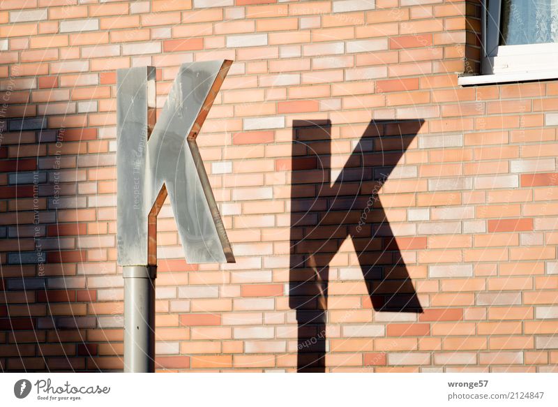 K K Mauer Wand Schriftzeichen Stadt braun schwarz silber Buchstaben Licht & Schatten Pylon Hausmauer Außenaufnahme Detailaufnahme Menschenleer Tag