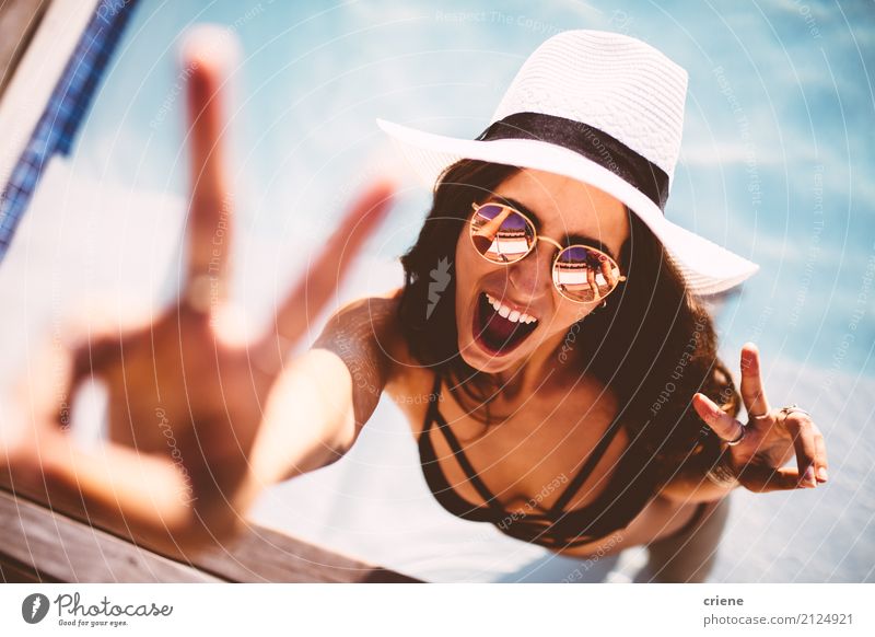 Glückliche junge Frau, die Friedenszeichen zeigt und Kamera betrachtet Lifestyle Freude Schwimmbad Freizeit & Hobby Ferien & Urlaub & Reisen Freiheit Sommer