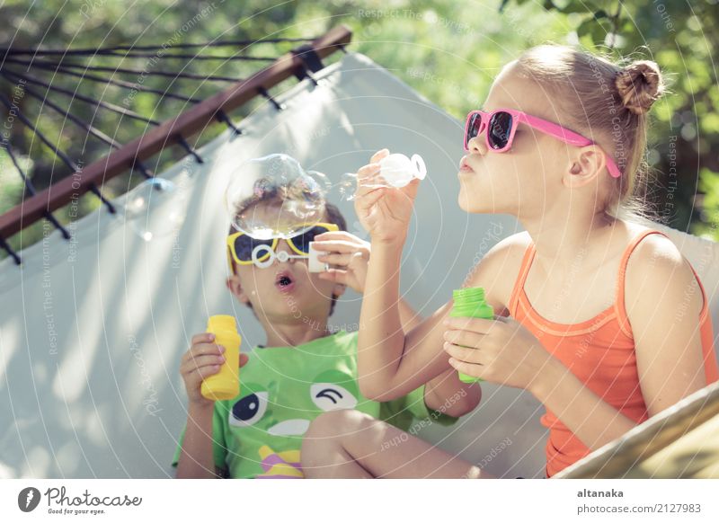 Zwei glückliche Kinder liegen auf einer Hängematte und spielen mit Seifenblasen. Lifestyle Freude Glück schön Erholung Freizeit & Hobby Spielen Freiheit Camping