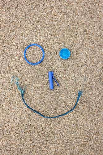 Plastik Strand-Fundstücke als lachendes Gesicht Sand machen Spielen Coolness Fröhlichkeit kaputt blau Tugend Verantwortung Freude Umwelt Umweltverschmutzung