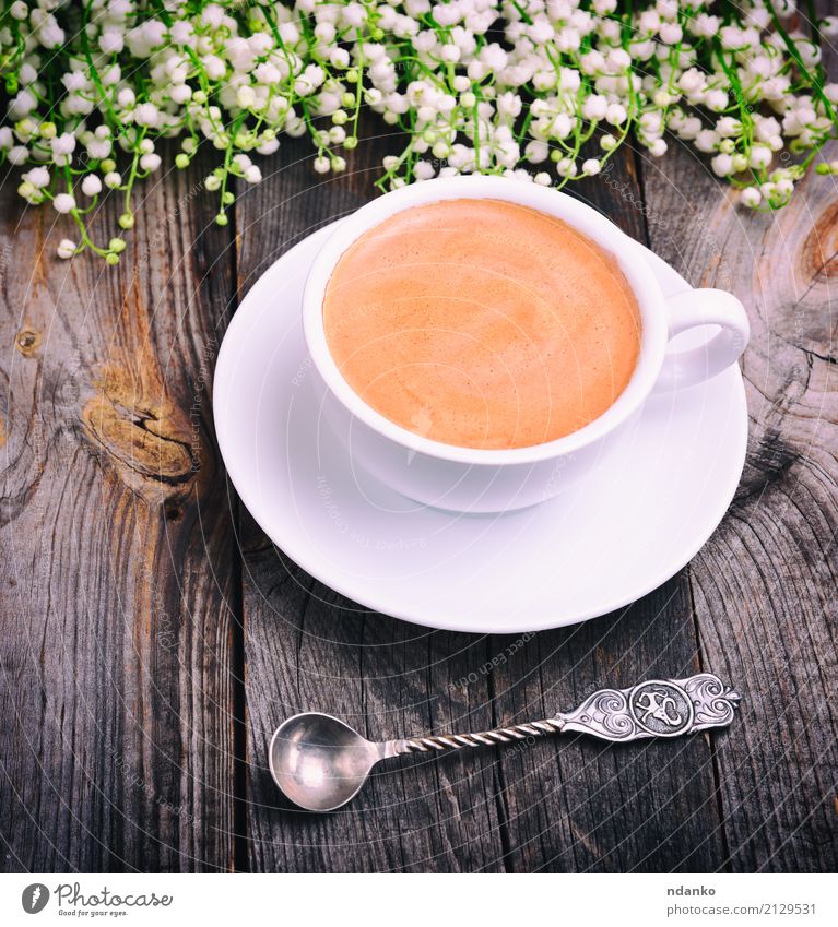 Tasse Kaffee und ein Eisenlöffel Kaffeetrinken Heißgetränk Becher Löffel Tisch Blume Blumenstrauß Holz heiß oben retro grau schwarz weiß Maiglöckchen Top