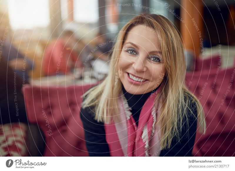 Attraktive Frau, die in einem Restaurant sitzt Glück Business PDA Erwachsene Mode Schal blond Lächeln sitzen dünn attraktiv mittleren Alters Bestseller