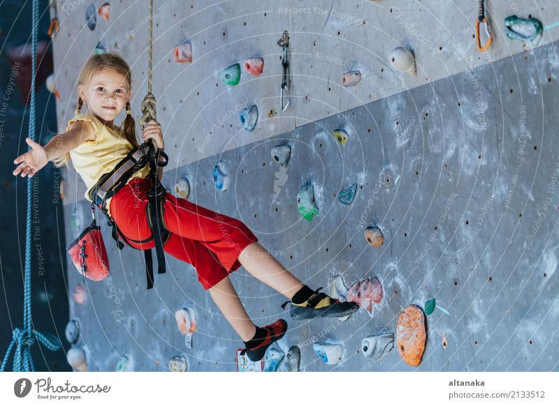 Kleines Mädchen klettert an einer Felswand im Innenbereich. Konzept des Sportlebens. Freude Freizeit & Hobby Spielen Ferien & Urlaub & Reisen Abenteuer Camping